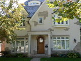 Centre hall house finished in white stucco with interesting stone details